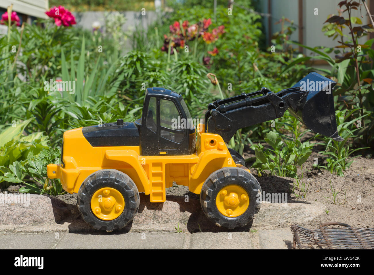 the plastic toy car costs against a bright flower bed Stock Photo
