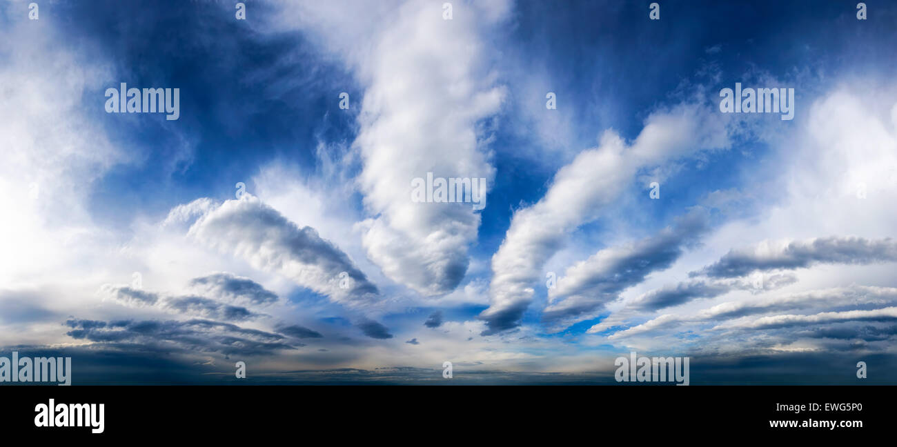 Sky panorama showing a fascinating cloudscape with deep blue color and white clouds Stock Photo