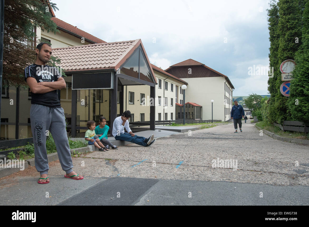 Freital, Germany. 25th June, 2015. Asylum seekers stand in front of their temporary accommodation in Freital, Germany, 25 June 2015. Stanislaw Tillich, Premier of the German State Saxony, has decided to intervene following protests and partly violent clashes surrounding a hotel that is to serve as a temporary accomodation for asylum seekers in Freital. He will visit the place on the same day to get a clearer picture of the current situation. PHOTO: PETER ENDIG/dpa/Alamy Live News Stock Photo