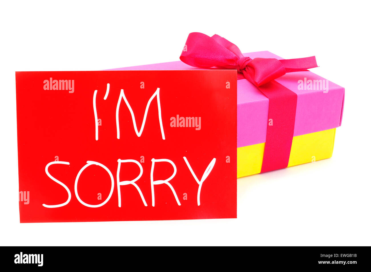 a gift box of different colors tied with a purple ribbon and a red card with the text I am sorry written in it, on a white backg Stock Photo