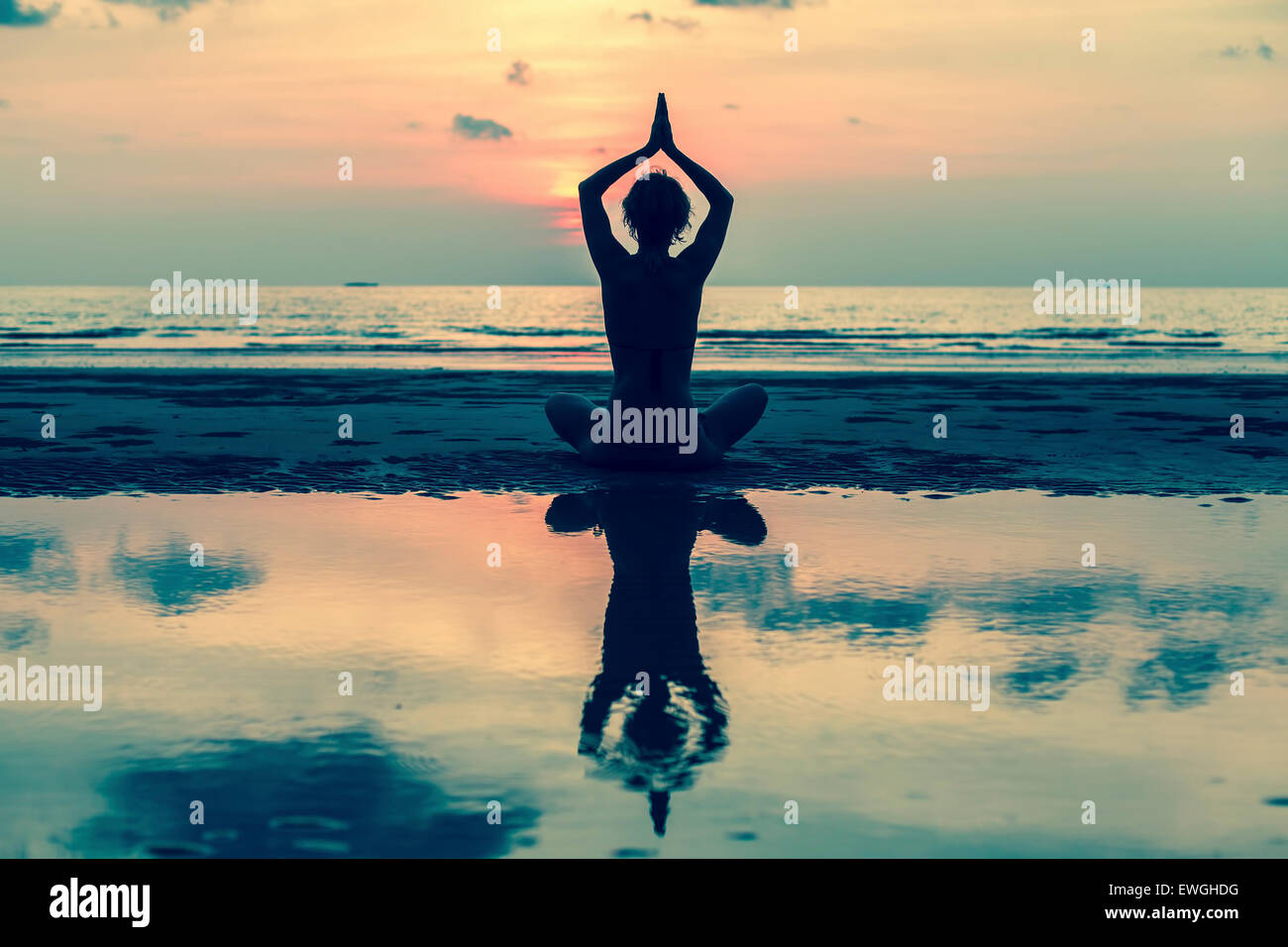 Silhouette of yoga woman sitting in lotus pose on the beach with ...