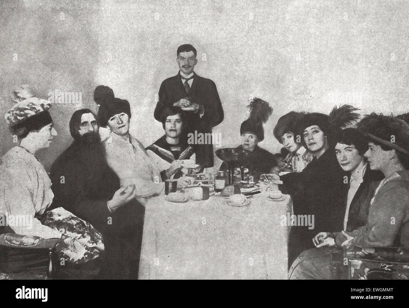The sinister monk Rasputin was assassinated before the outbreak of the Revolution.  Yet no figure was more prominent during the evil days which preceded it, among the pro German traitors of the court.  Here he is drinking tea with a characteristic group of woman admirers, circa 1910 Stock Photo