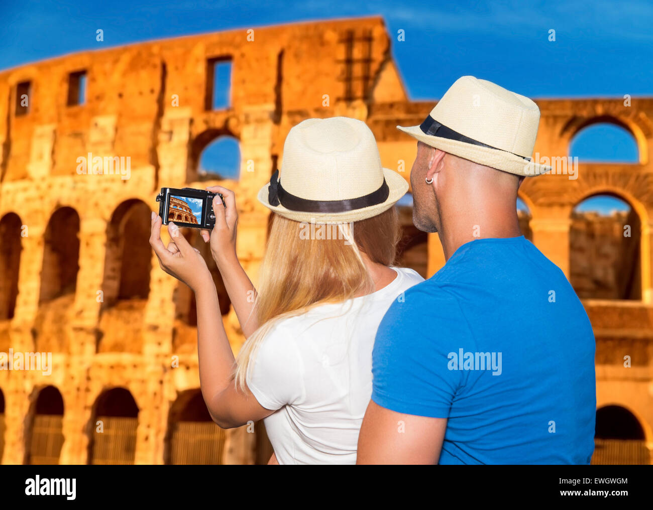 Back side of young happy couple taking picture of beautiful gorgeous ancient Coliseum, honeymoon vacation in Rome, Italy, Europe Stock Photo