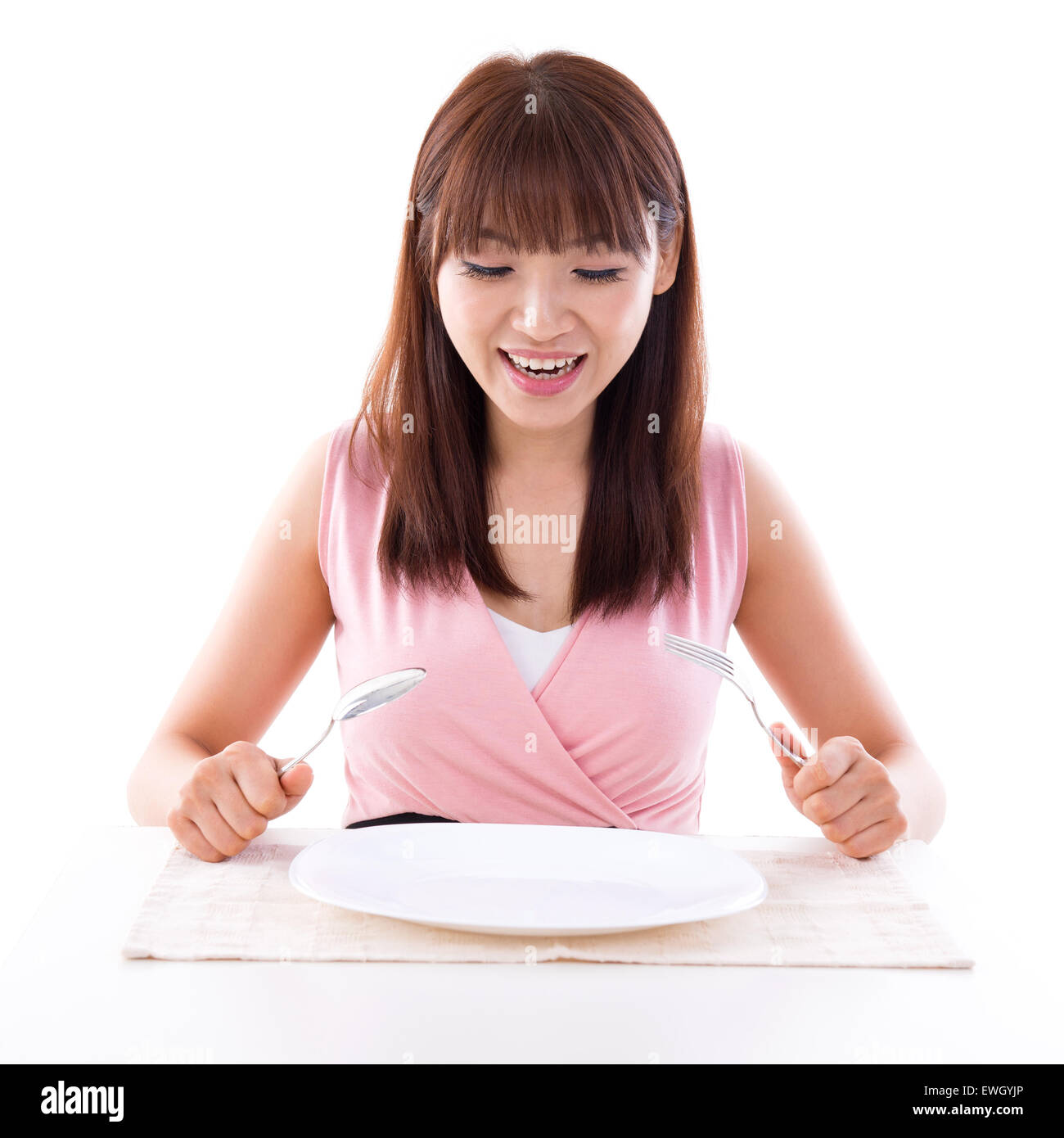 Asian girl holding fork and spoon with surprised expression, empty