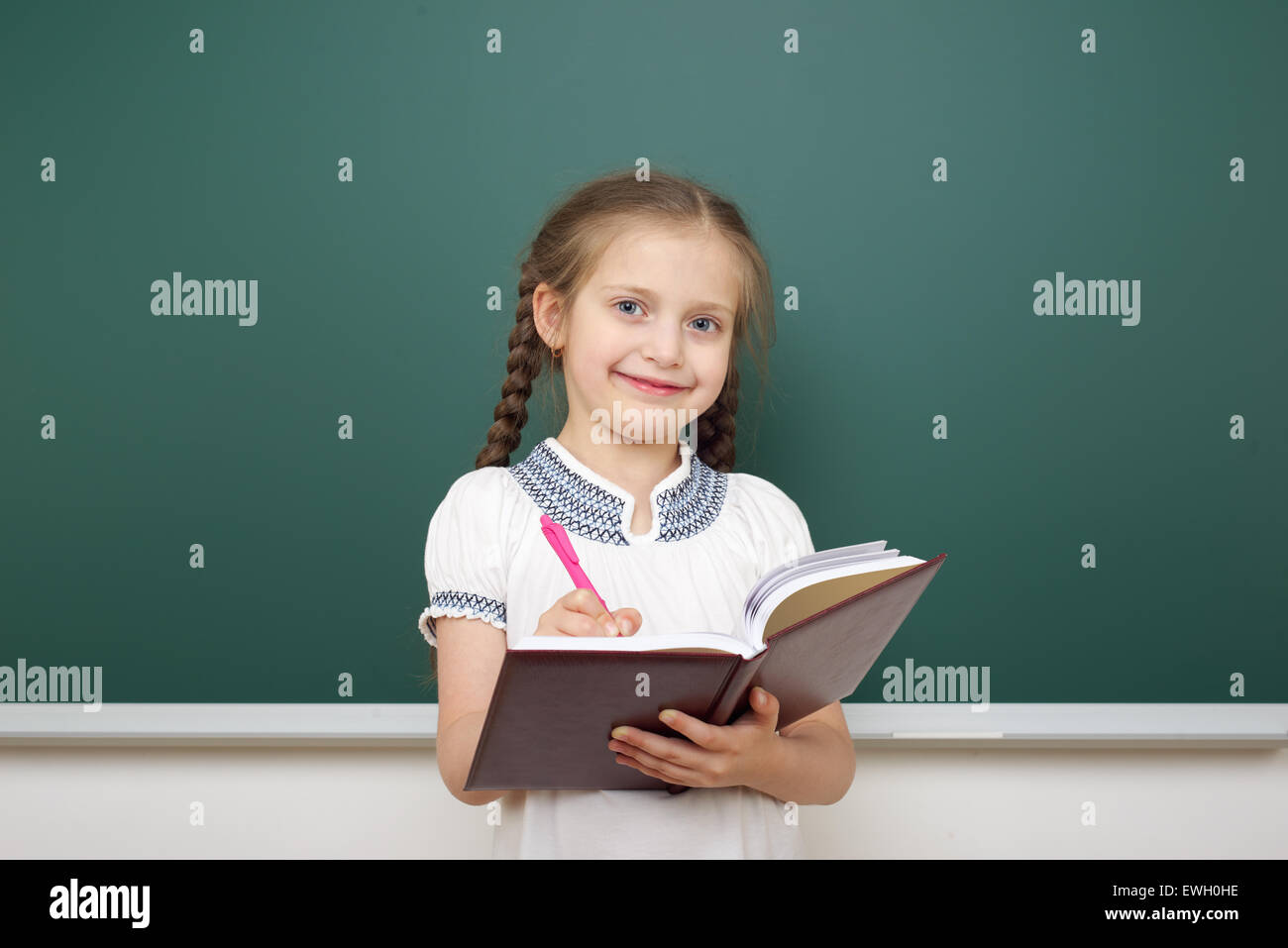 Schoolgirl with book near the school board Stock Photo - Alamy