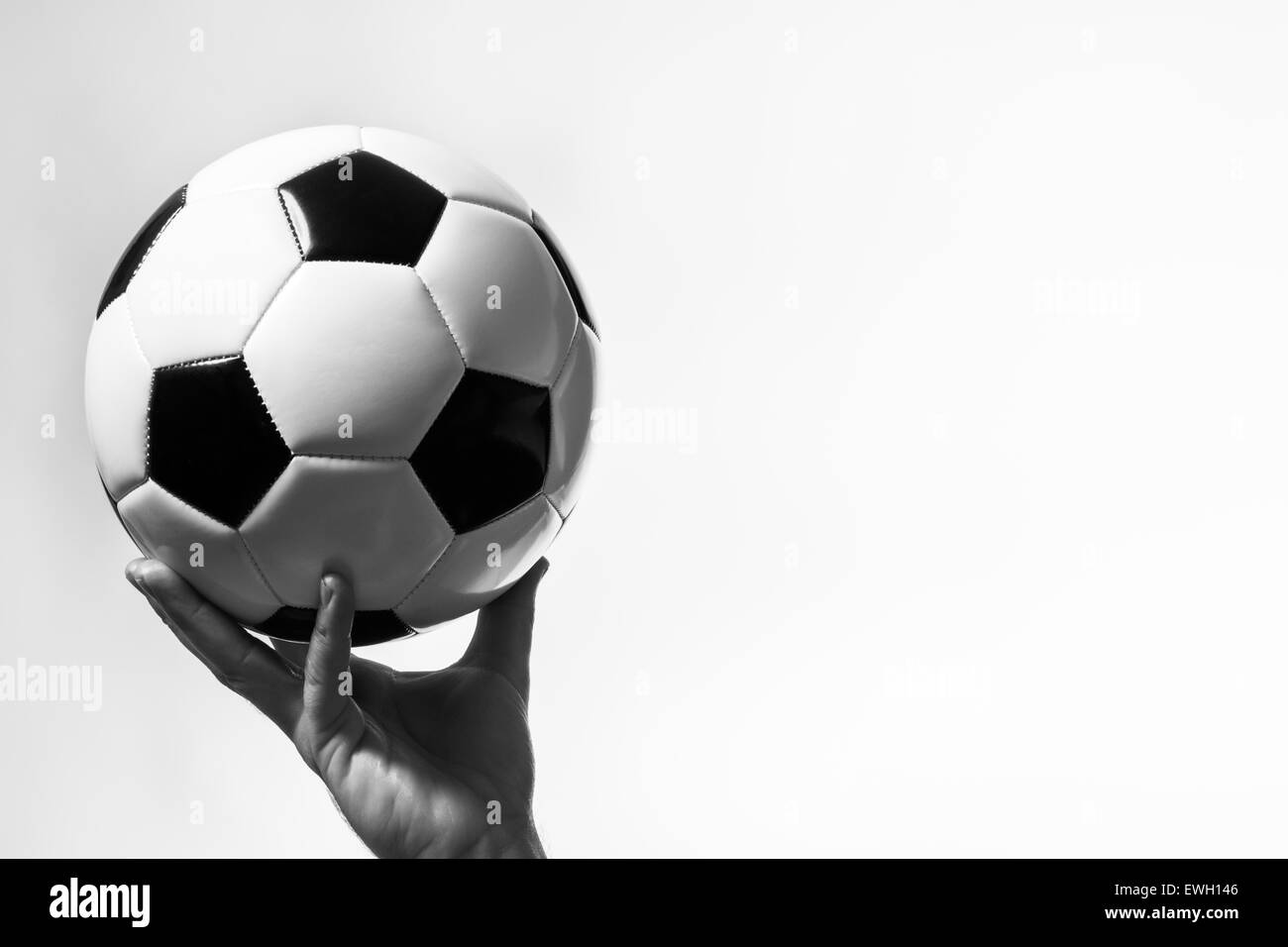 male hand holding up a traditional black and white football Stock Photo