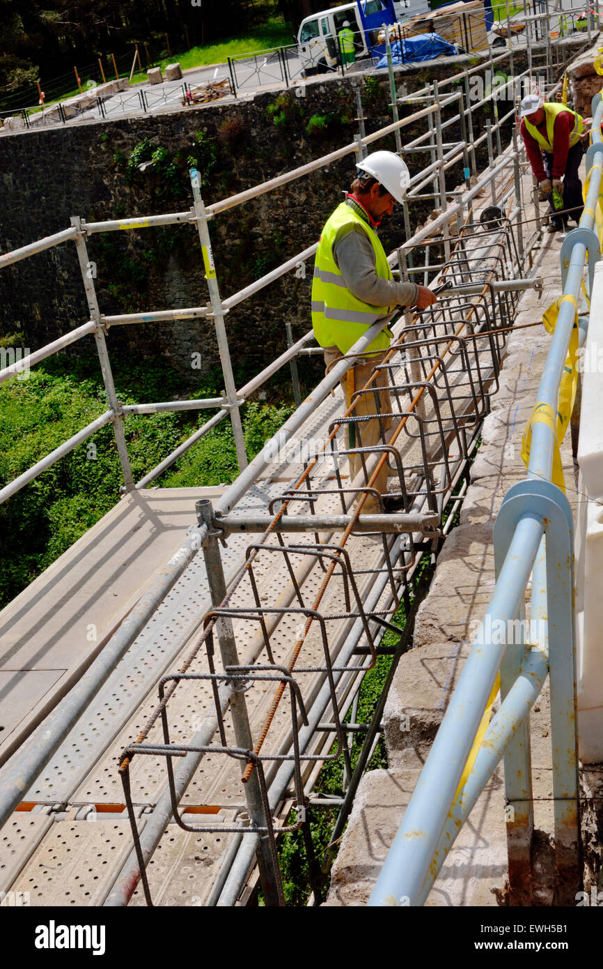 Workers rebuilding protective wall with rebar for reinforced concrete