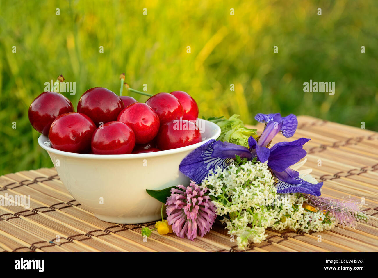 Full bowl of ripe cherries with wild forest flowers Stock Photo Alamy