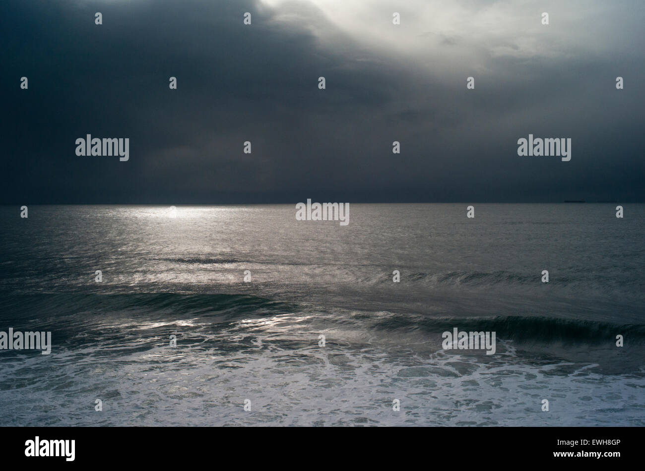 Dark sky in winter with moonlight reflected on the North Atlantic Ocean as a big swell and storm approaches. Stock Photo