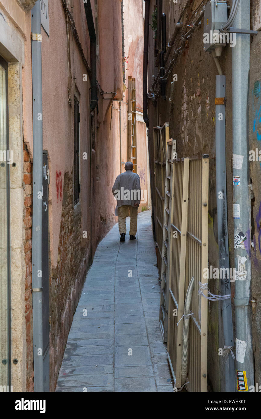 Elderly gentleman walking down a narrow alleyway in Venice Italy Stock Photo