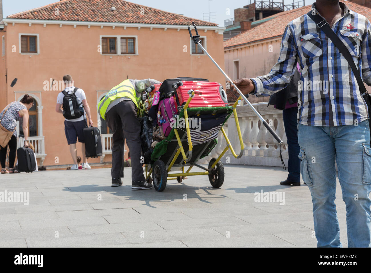 A luggage porter carrying luggage over a bridge in Venice Italy Stock