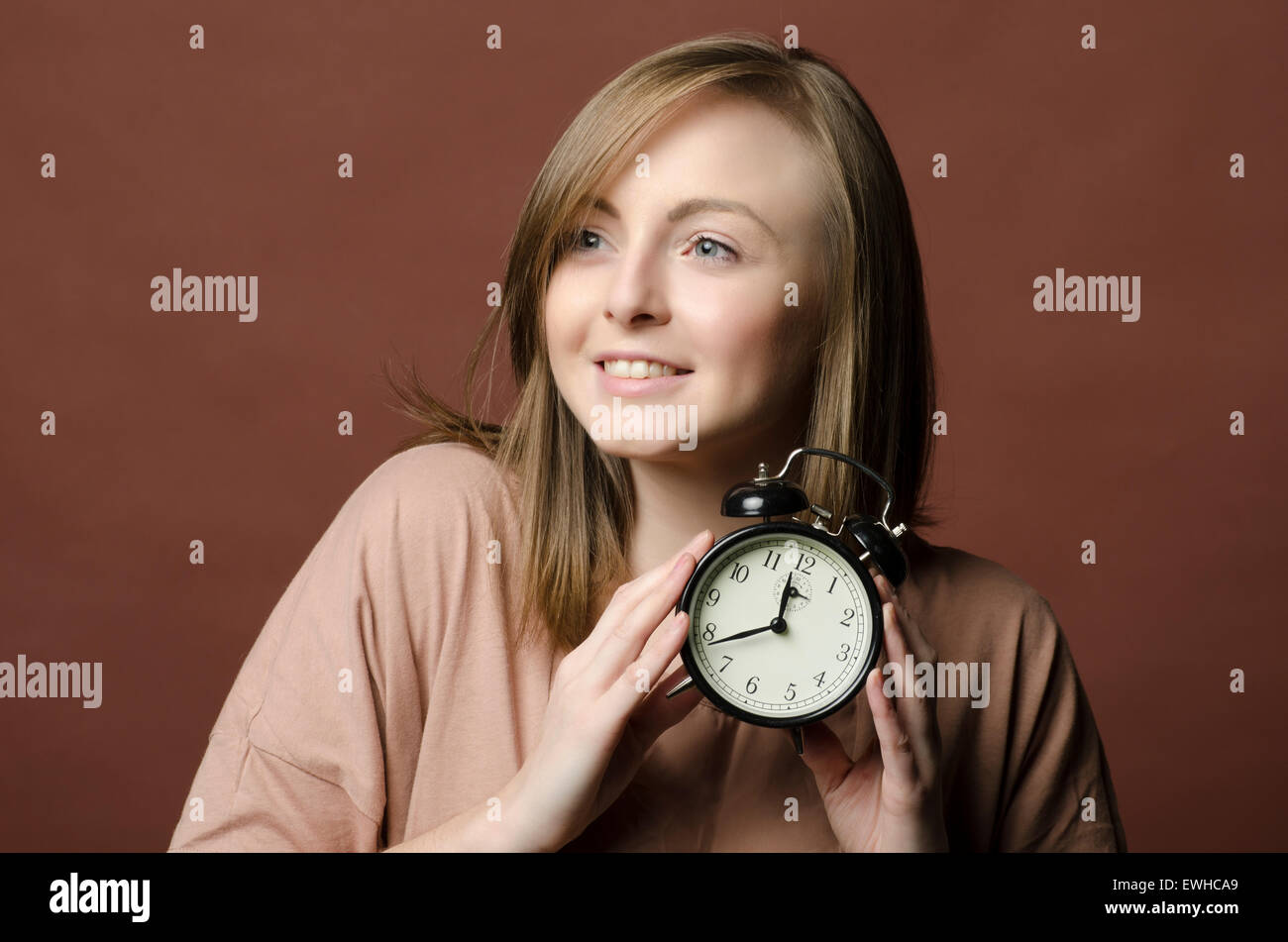 Punctual young woman holding an alarm clock Stock Photo