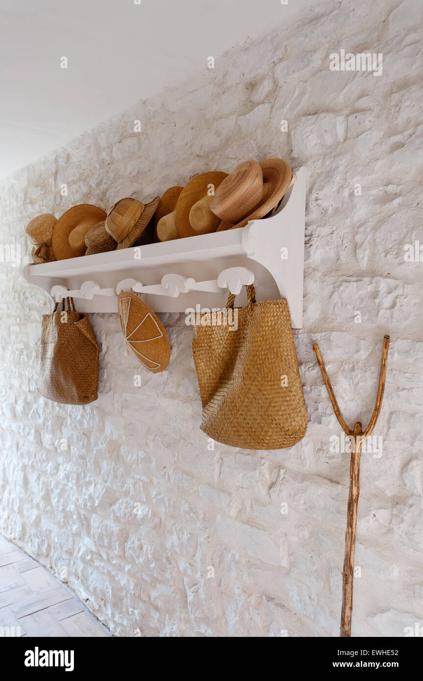 Straw sun hats on wooden rack against white stone wall Stock Photo - Alamy