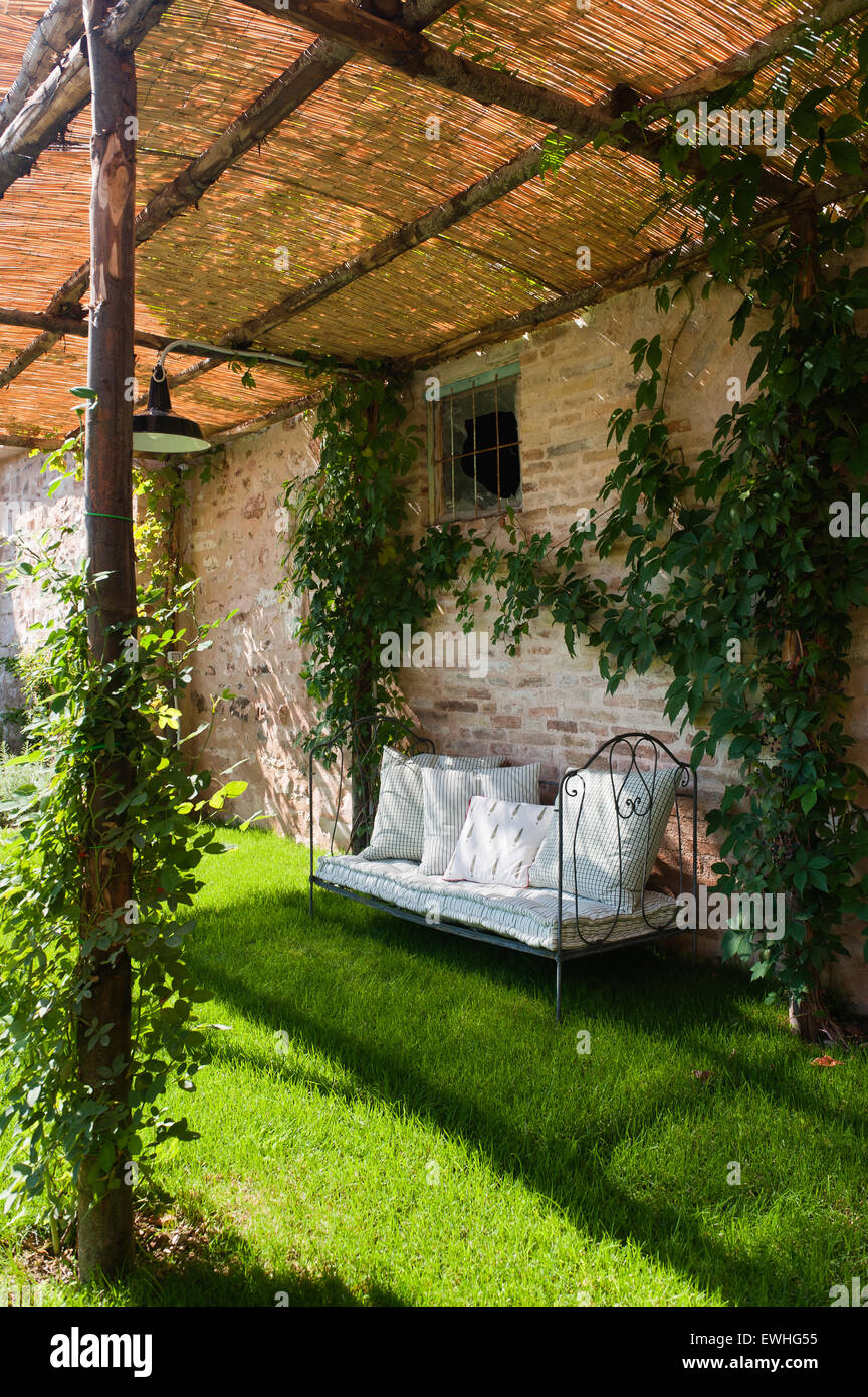 Iron garden bench under wicker awning in garden of Umbrian villa Stock Photo