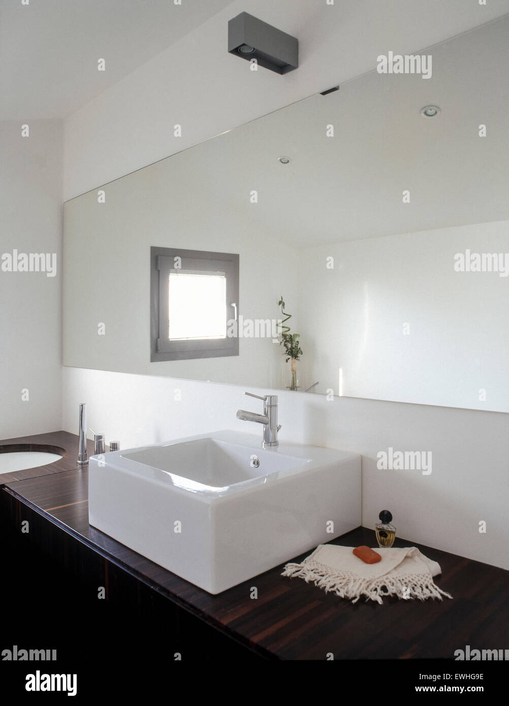 foreground of washbasin in the modern bathroom with wooden top and a large mirror Stock Photo