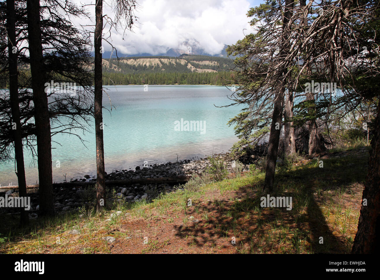 A peaceful scene in the Rockies showing a lake in the foreground and the mountains behind Stock Photo