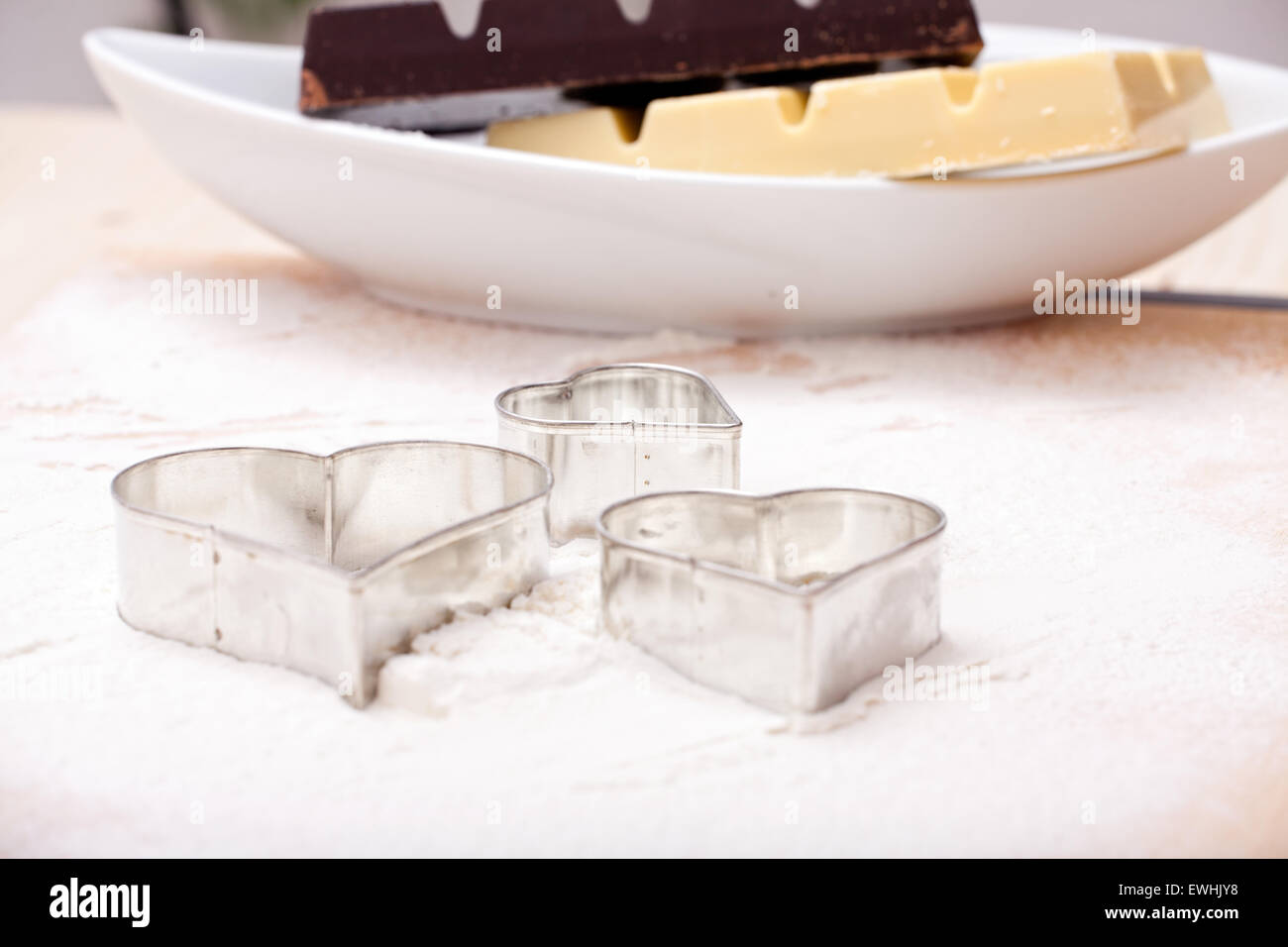 Cookie cutters and white and dark Couverture chocolate on floured baking mat Stock Photo
