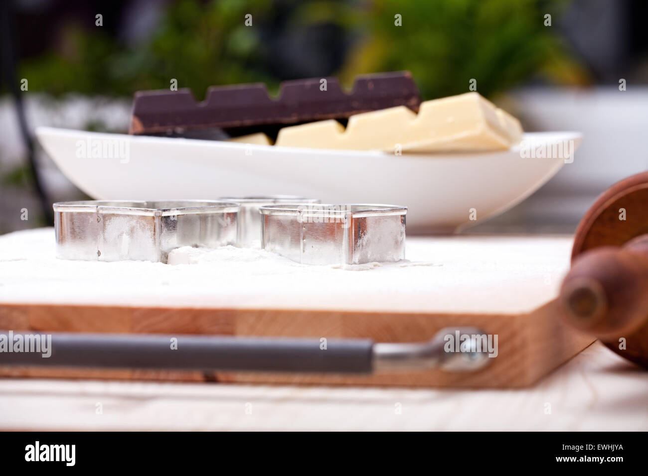 Cookie cutters and white and dark couverture chocolate on floured baking board Stock Photo