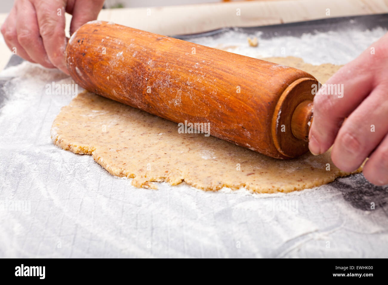 Roll out with wooden rolling pin the biscuit dough on the baking mat Stock Photo