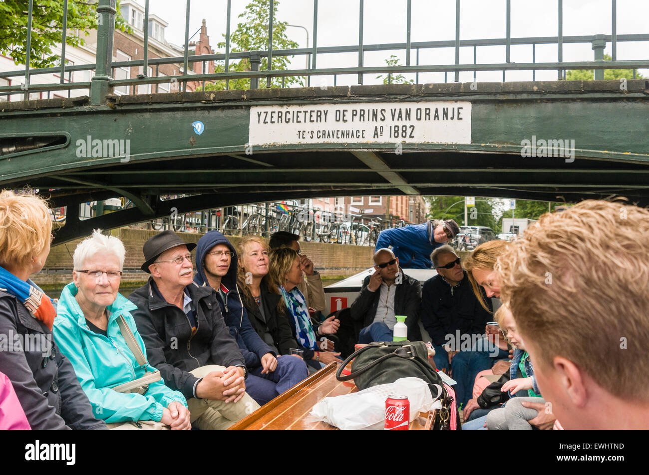 Tourists on a canal boat tour mind their heads after passing underneath a low bridge in the Hague, Netherlands Stock Photo