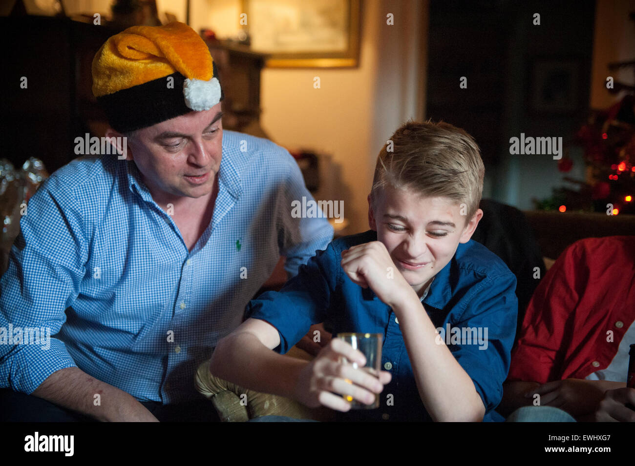 An uncle lets his nephew try his first taste of whiskey Stock Photo