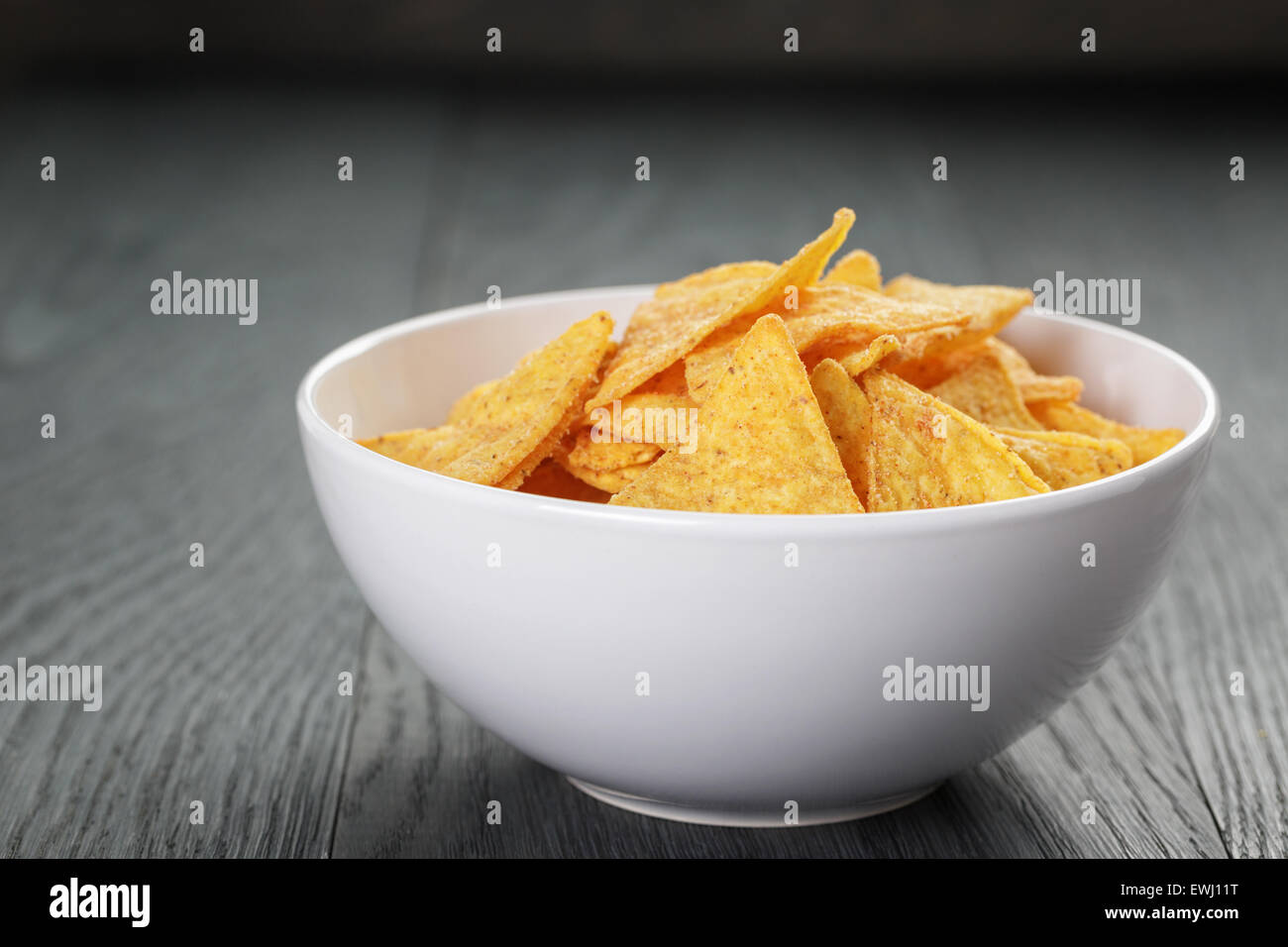 tortilla chips in white bowl on wooden table Stock Photo