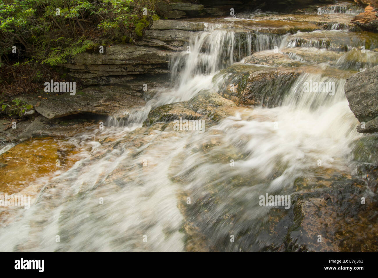 rushing stream through granite boulders after summer storm Stock Photo