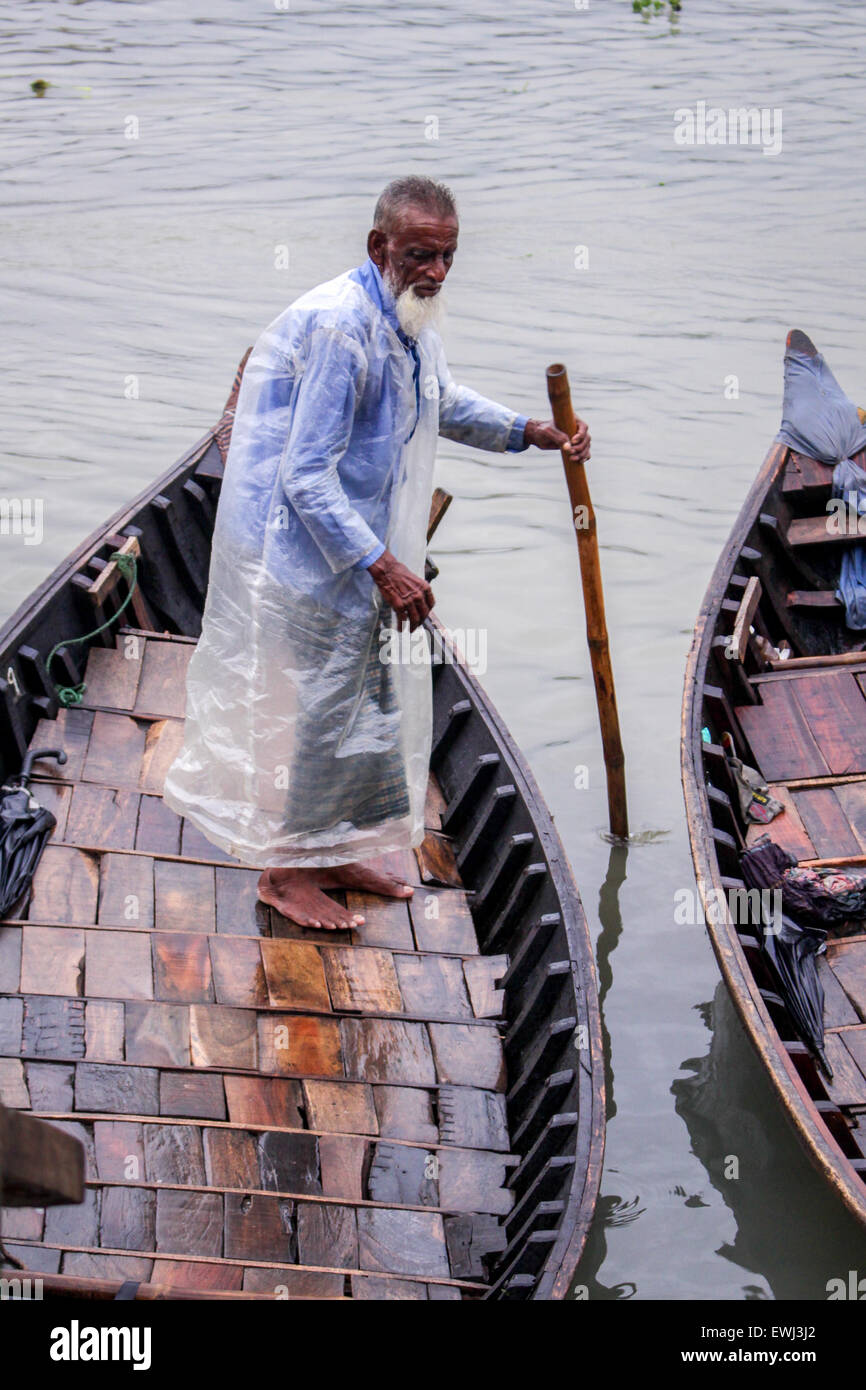Dhaka, Bangladesh. 26th June, 2015. An old boatman wears raincoat made