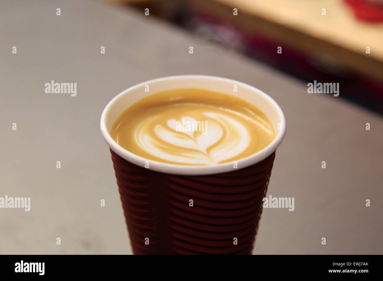 Side view of latte art coffee with heart figure on, in take away paper