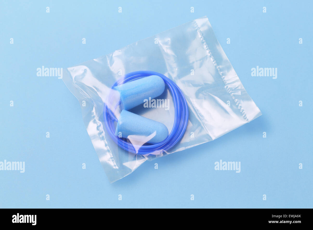 Ear Plugs in Sealed Plastic Bag on Blue Background Stock Photo