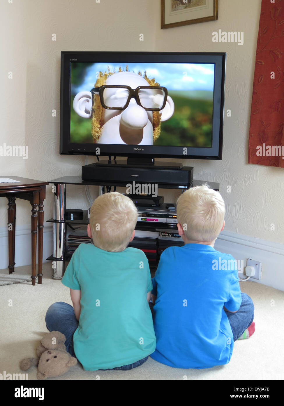 2 little blonde boys watching Shaun the Sheep Movie on TV Stock Photo