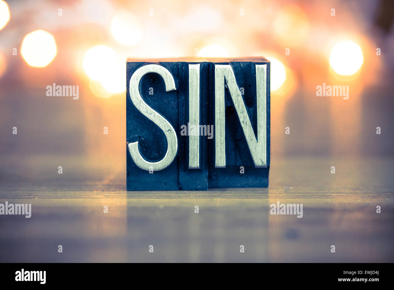 The word SIN written in vintage metal letterpress type on a soft backlit background. Stock Photo