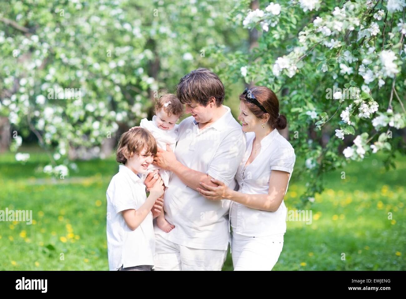 Happy young family in a blooming apple tree garden Stock Photo