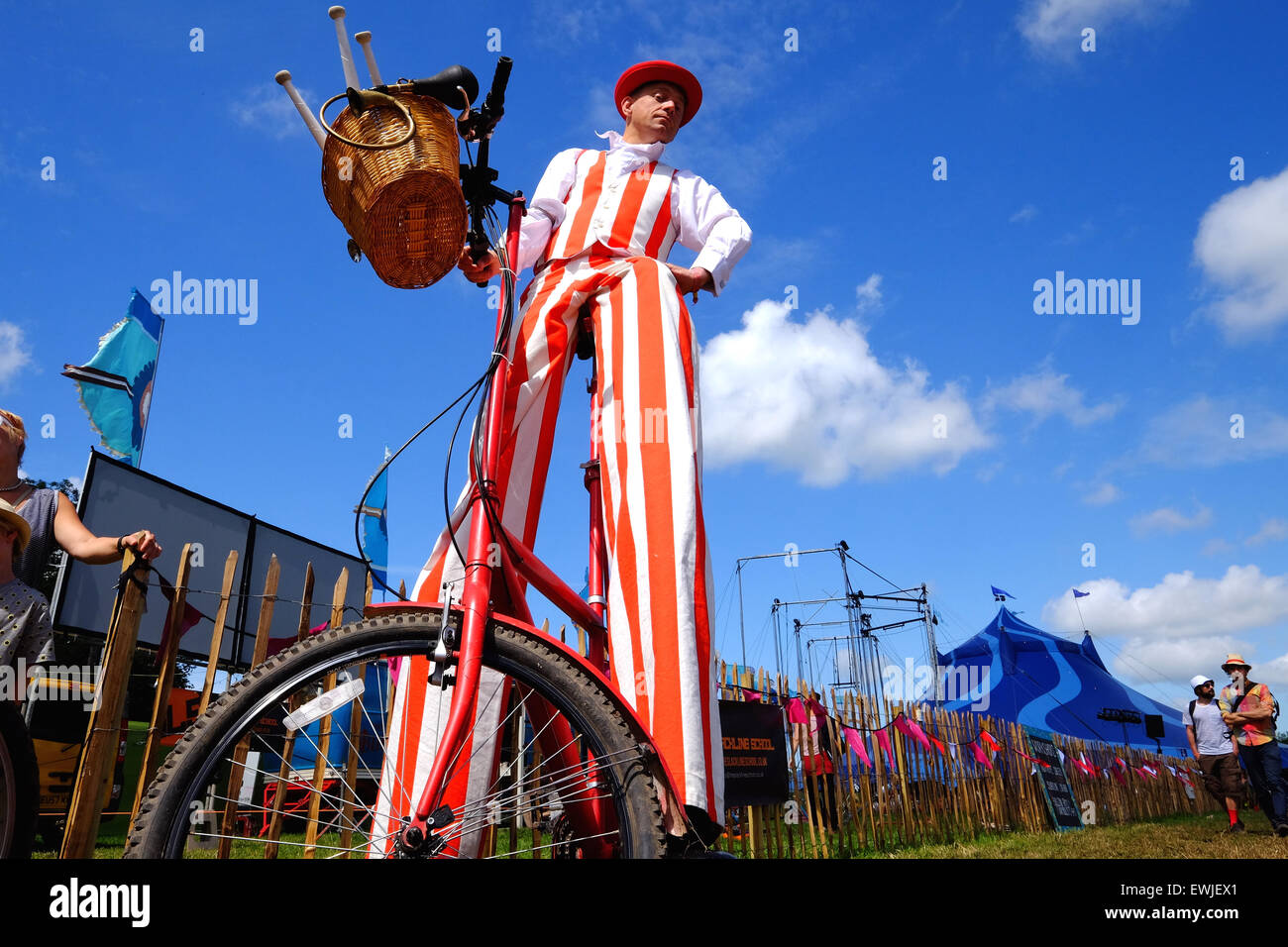 Glastonbury Festival, Somerset, UK. 27 June 2015. Rain, what rain. Stilt wearing bicycle riders prepare to entertain the crowds in the Theatre & Circus area as Saturday turns into a scorcher. Credit:  Tom Corban/Alamy Live News Stock Photo
