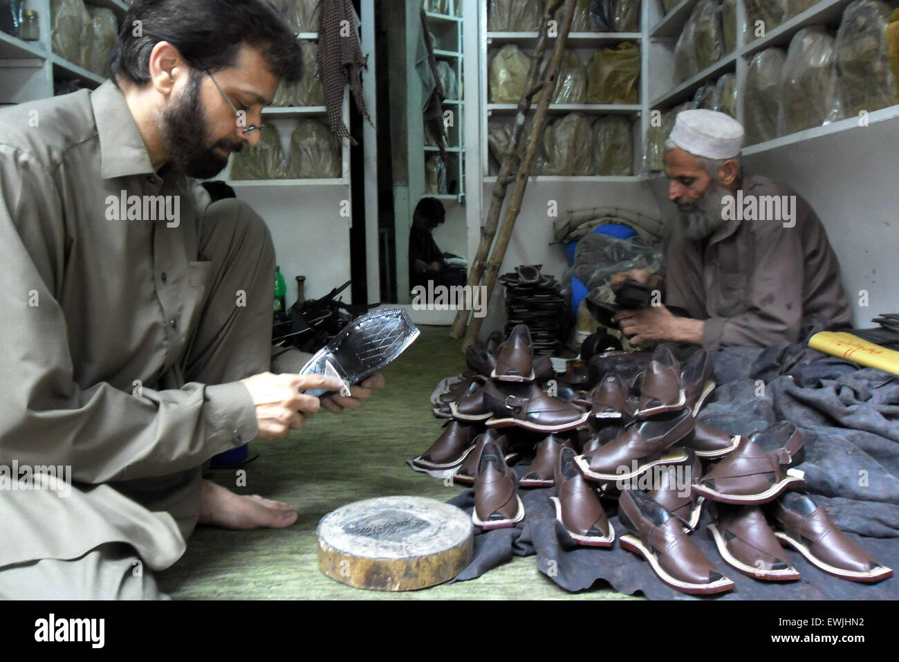 Peshawar. 27th June, 2015. Pakistani people make traditional Peshawari Chappal at a workshop in northwest Pakistan's Peshawar, June 27, 2015. Peshawari Chappal is a traditional footwear of Pakistan, worn especially by Pashtuns in the Khyber Pakhtunkhwa region of Pakistan. © Ahmad Sidique/Xinhua/Alamy Live News Stock Photo