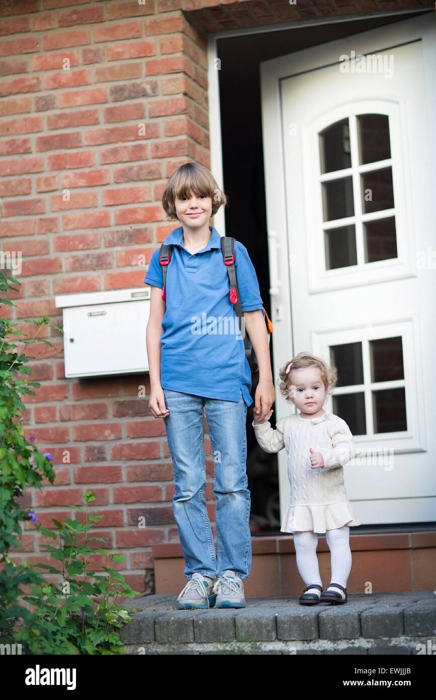 Brother And Baby Sister Leaving Home On Their First Day To School And Brother And Baby Sister Leaving Home On Their First Day To School And