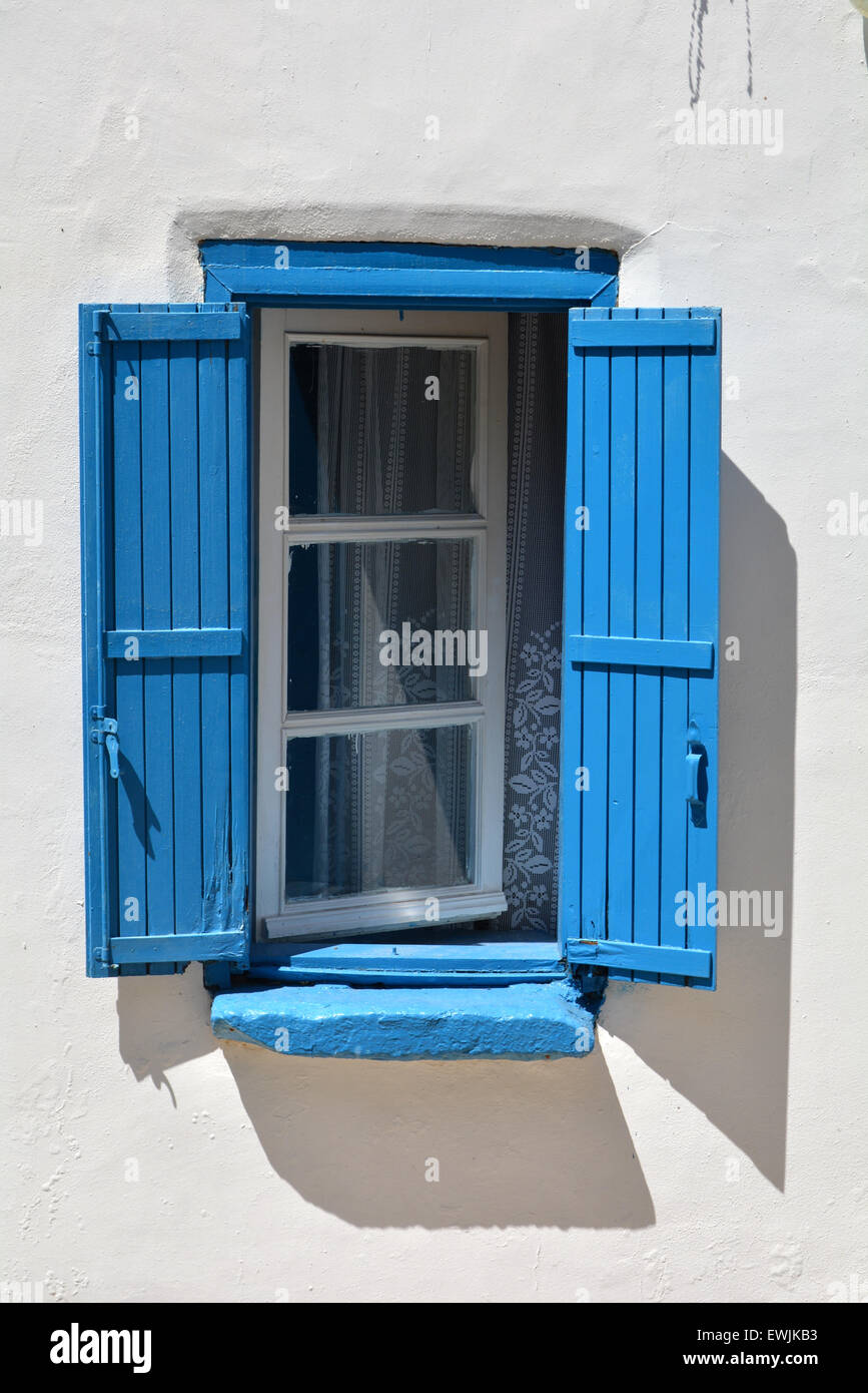 Open window with blue shutters in bright sunshine in the village of Loutro, Crete Greece Stock Photo