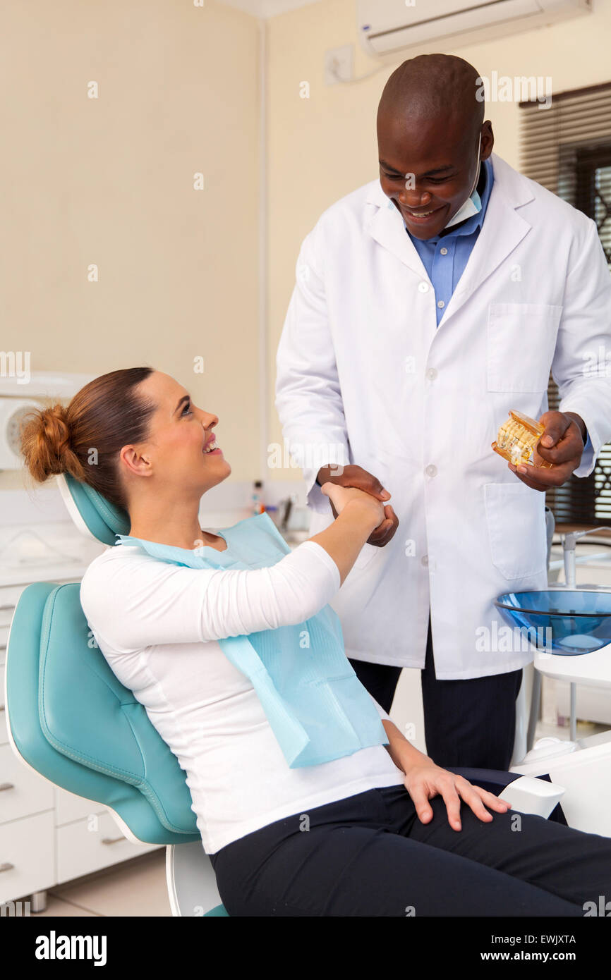 cheerful young woman shaking hands with dentist after teeth checkup Stock Photo