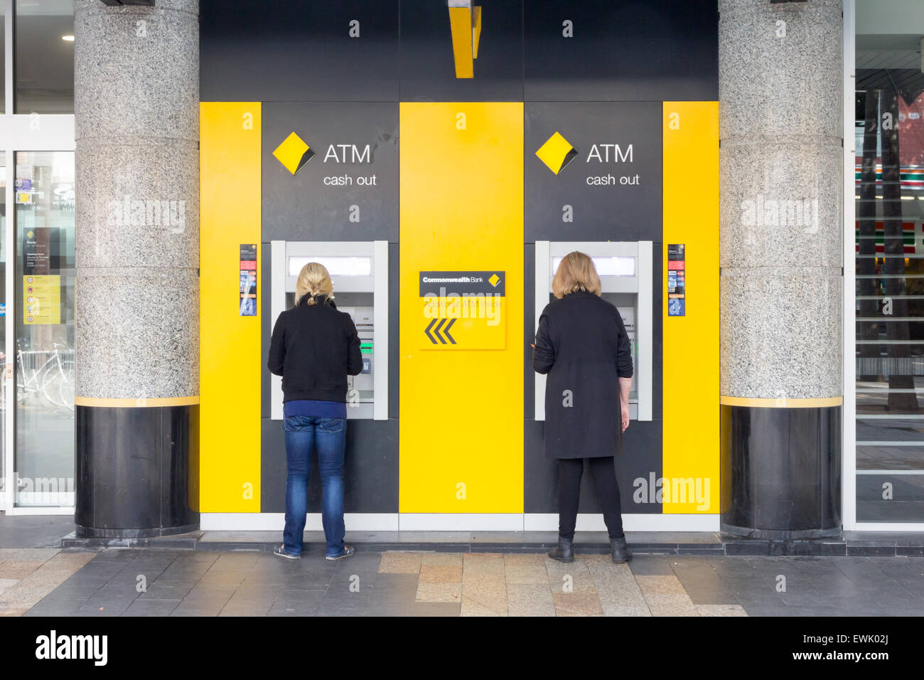 Manly, Australia-June 12th 2015: 2 women withdraw cash from an ATM machine. All banks now have external ATM machines. Stock Photo