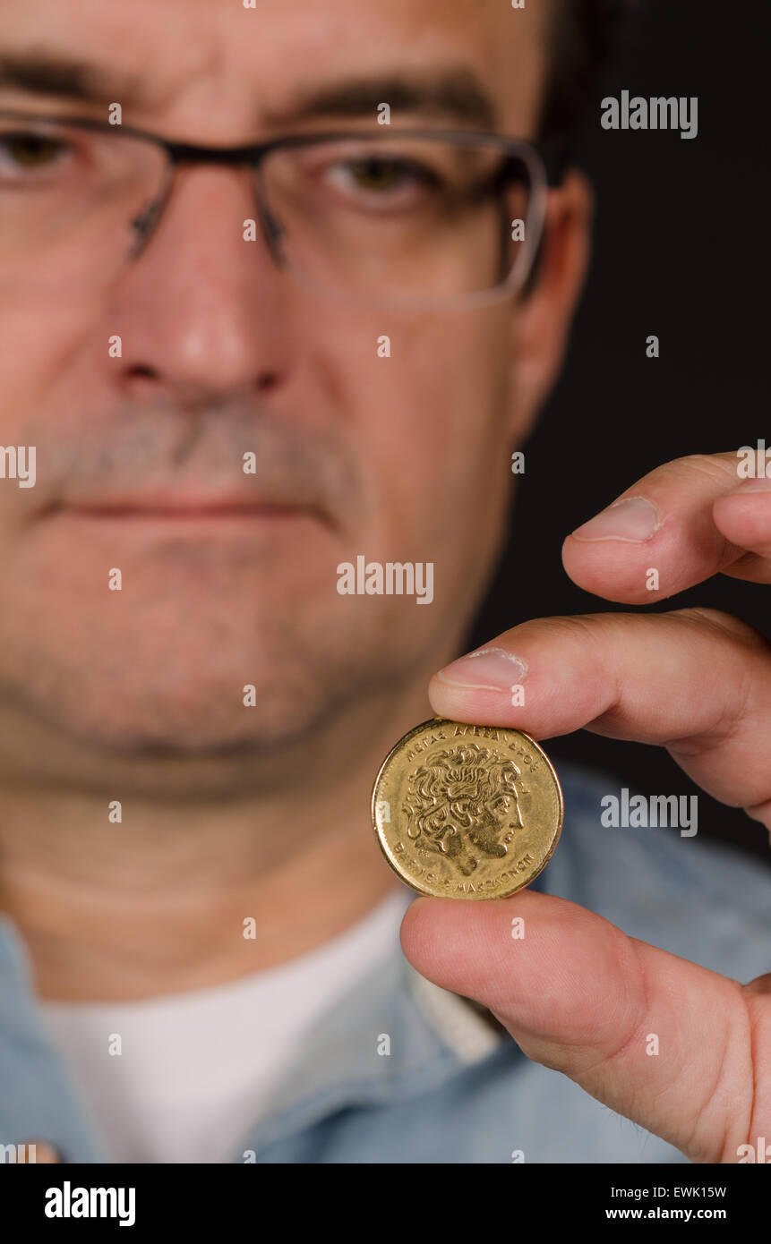 Man holding a 100 Greek drachma coin Stock Photo