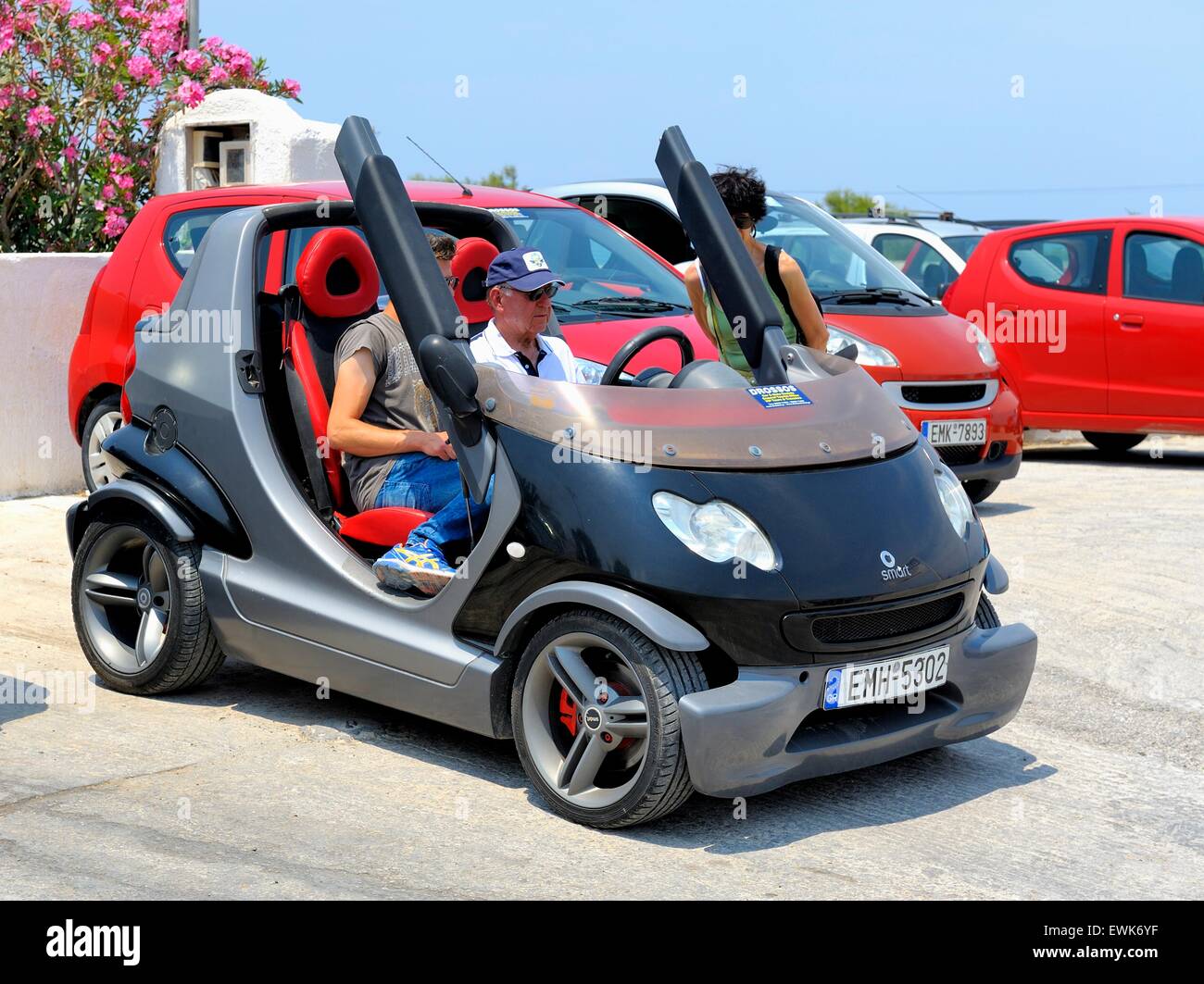 A car hire employee takes a tourist through the controls of a smart car. Stock Photo