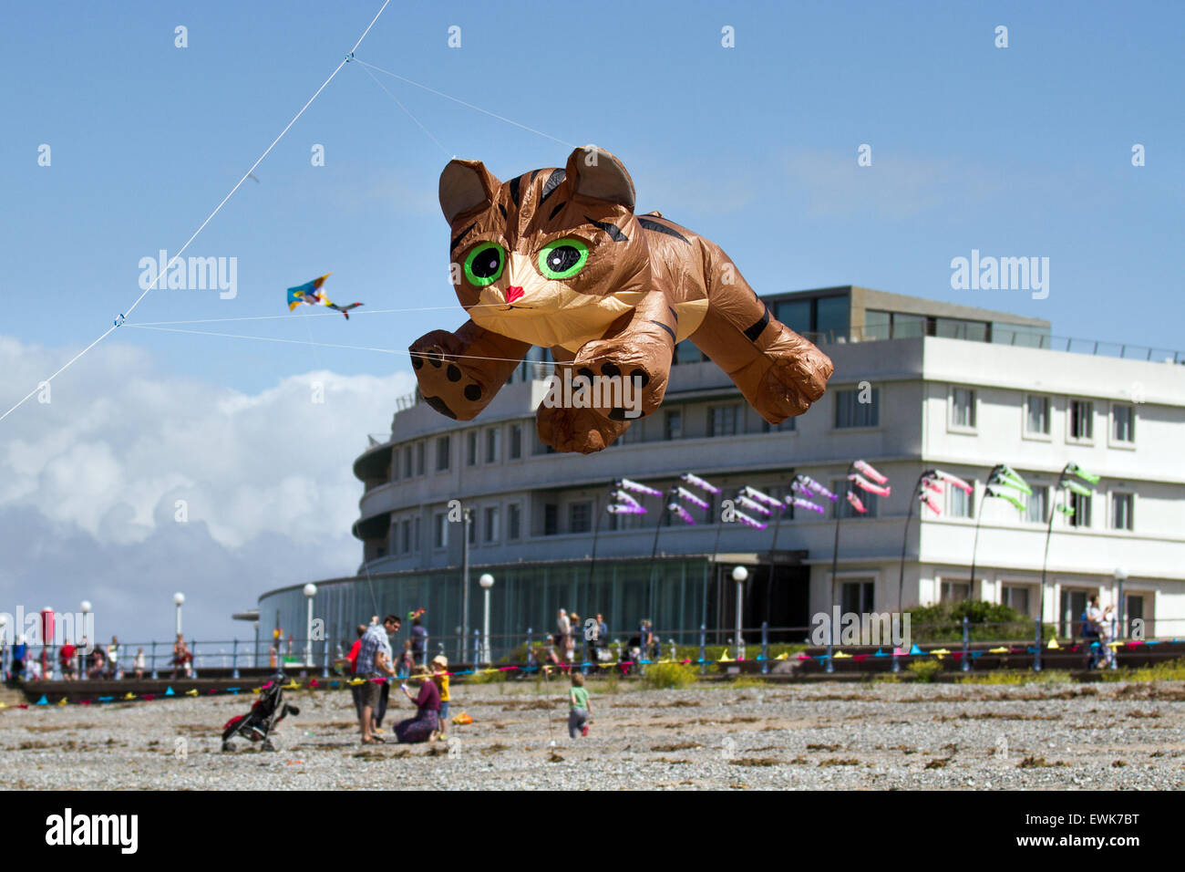 Morecambe, Lancashire, UK 27th June, 2015. Catch The Wind Kite Festival an annual festival on Morecambe seafront, when for the whole day the skies are full of the most spectacular shapes, colours and pussycat animal creations. Featured were single line show kites of all kinds and sizes, including a massive 40 feet tall long large inflatable brown Cat guaranteed to scare the heck out of any animals on the beach, seen here flying over the Midland Hotel. Stock Photo