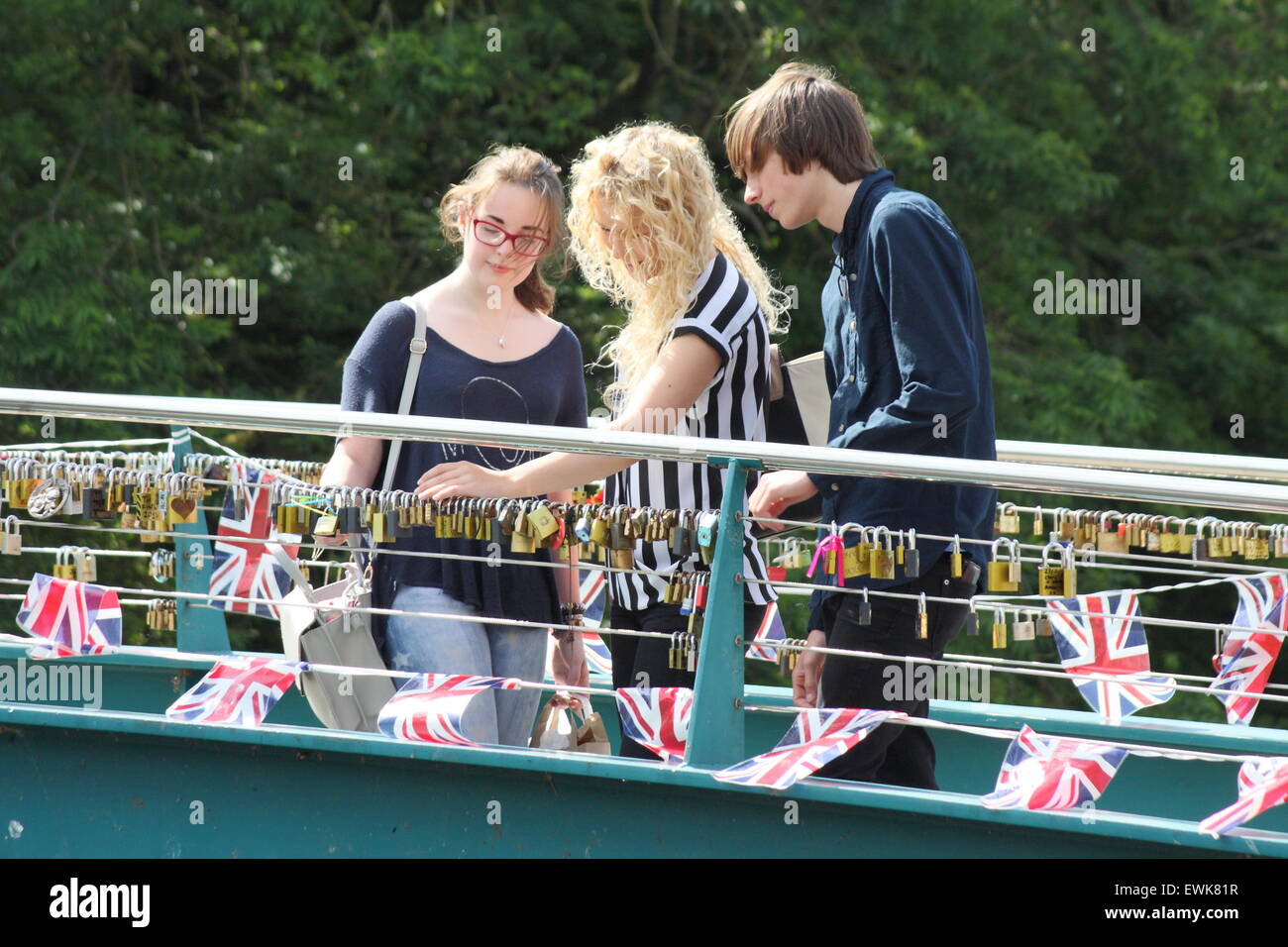 Young people look at lov3e locks on a bunting strewn bridge over the River Wye in Bakewell Derbyshire Stock Photo