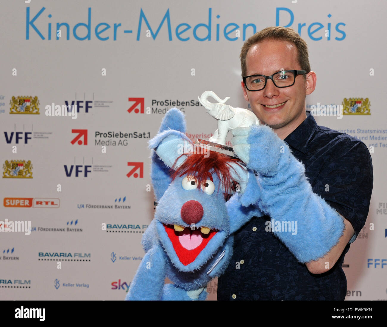 Munich, Germany. 28th June, 2015. Puppeteer Martin Reinl with the puppet Woozle rejoices over his trophy at the ceremony for the Children's Media Award 'The White Elephant' at the Munich Film Festival in Munich, Germany, 28 June 2015. Reinl received the award for 'Best TV Format' for the show 'Woozle Goozle.' Photo: Ursula Dueren/dpa/Alamy Live News Stock Photo