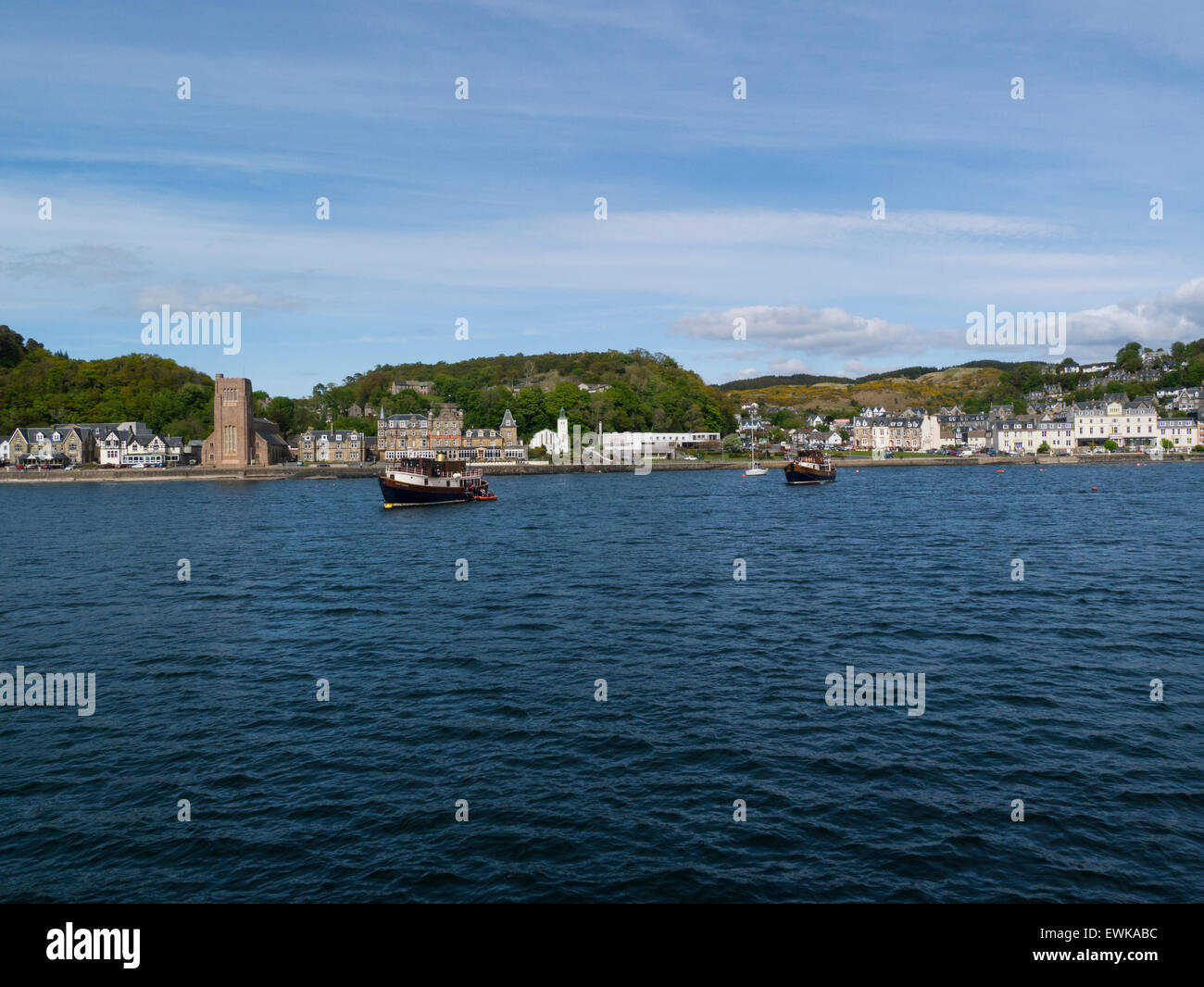 View historic sea front of popular resort town Oban Argyll and Bute Scotland from ferry on Sound of Kerrera on a lovely May day weather blue sky Stock Photo