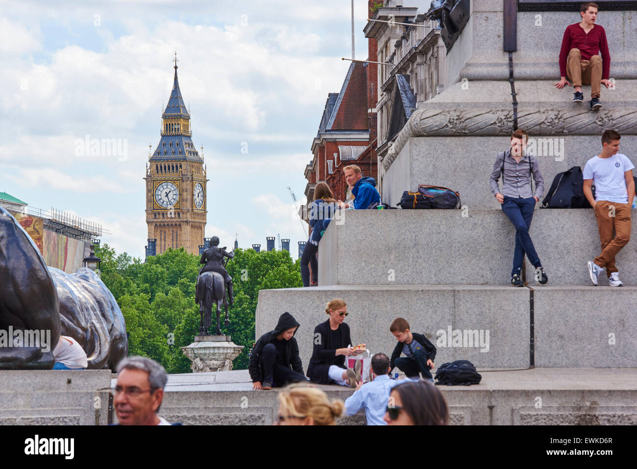 LONDON, UK - JUNE 15: Tourists sitting on the steps of Trafalgar Square, with Big Ben in the background. June 15, 2015 in London Stock Photo