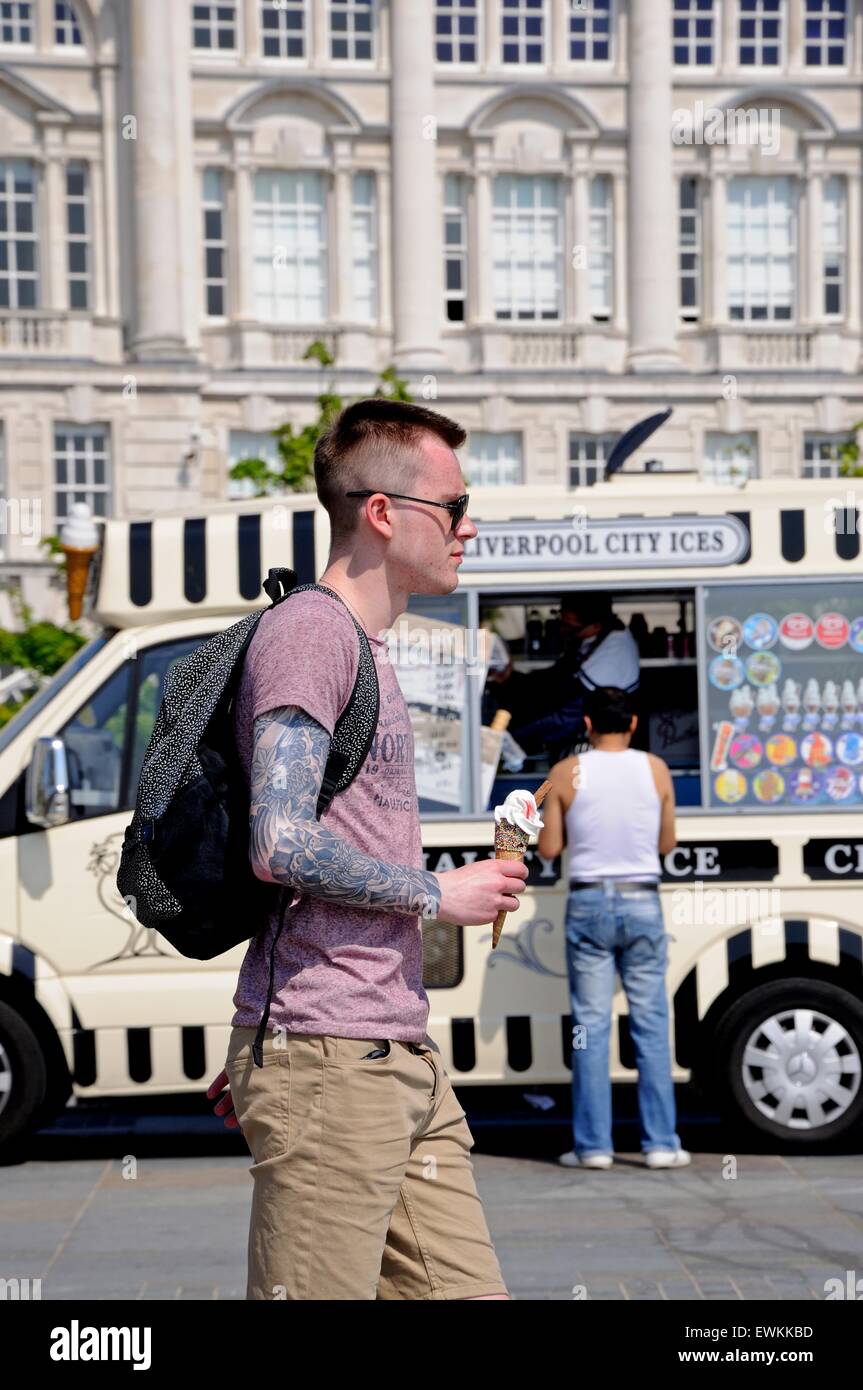 Young man with an ice cream walking past an ice cream van by the quayside, Liverpool, Merseyside, England, UK, Western Europe. Stock Photo