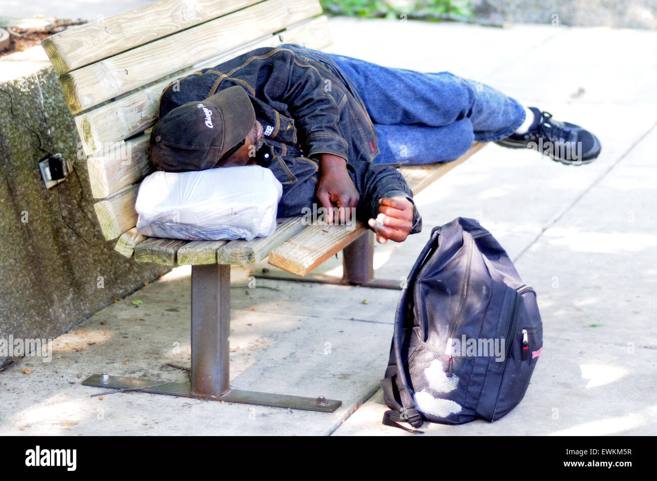 Homeless man sleeping on bench in a public park Stock Photo