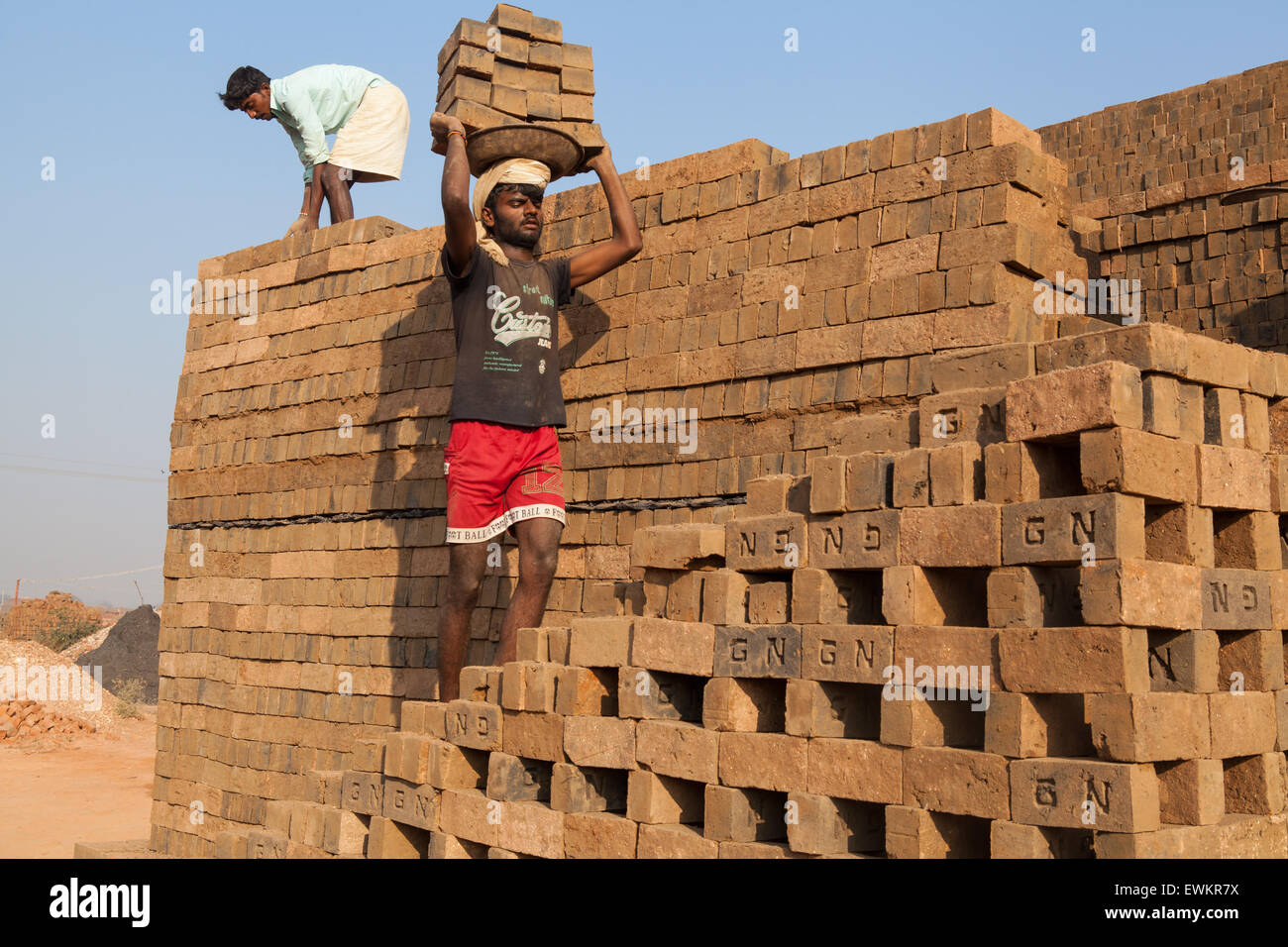 Male worker carrying bricks on his head at a brick factory in Harihar Stock Photo