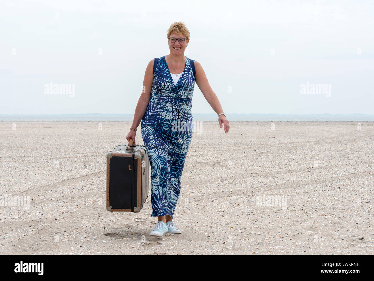woman with old vintage used suitcase walking on the beach Stock Photo
